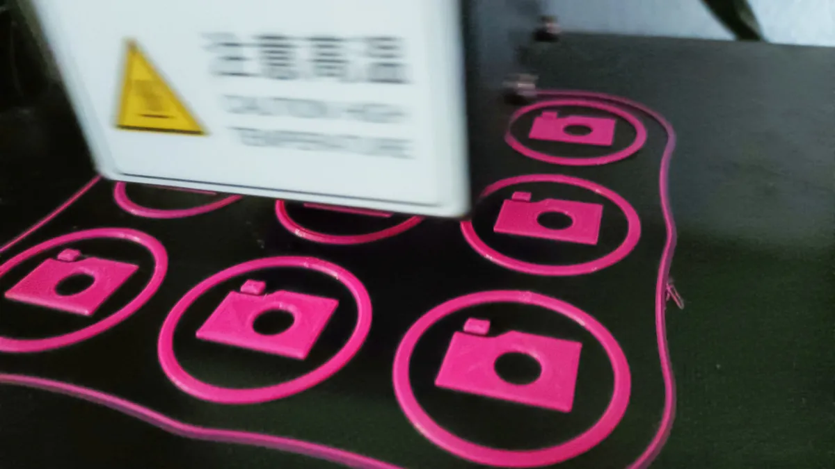 Freshly printed pink parts on a 3D printer bed, with the layers in view.