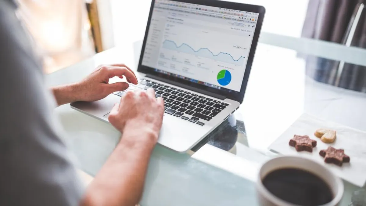 A laptop showing data charts, with a cup of coffee beside it.