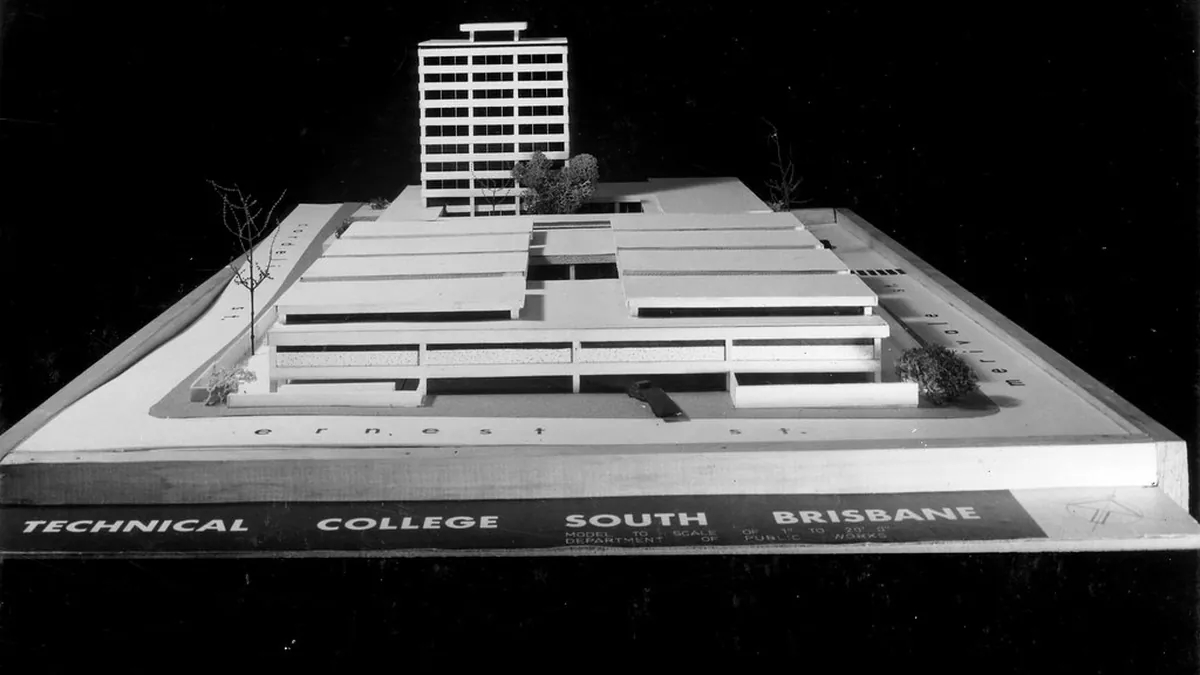 Maqueta blanca de un edificio sobre una peana, fotografiada de lado.