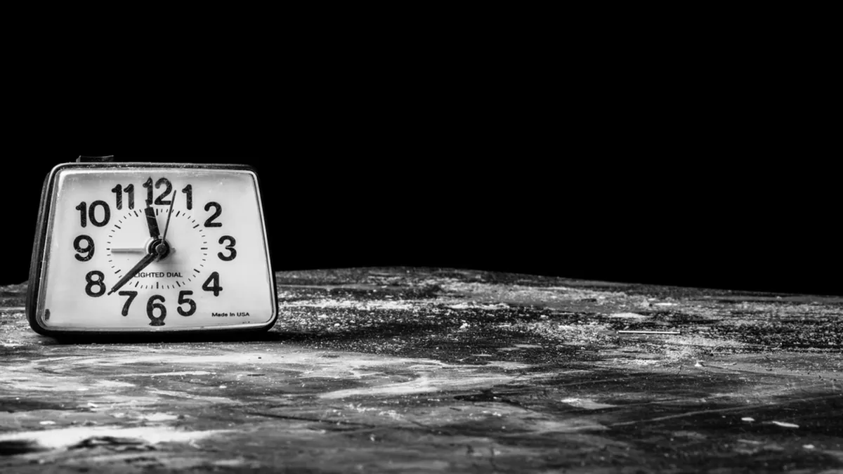 Despertador de mesa antiguo sobre una superficie gastada, fotografiado en blanco y negro.