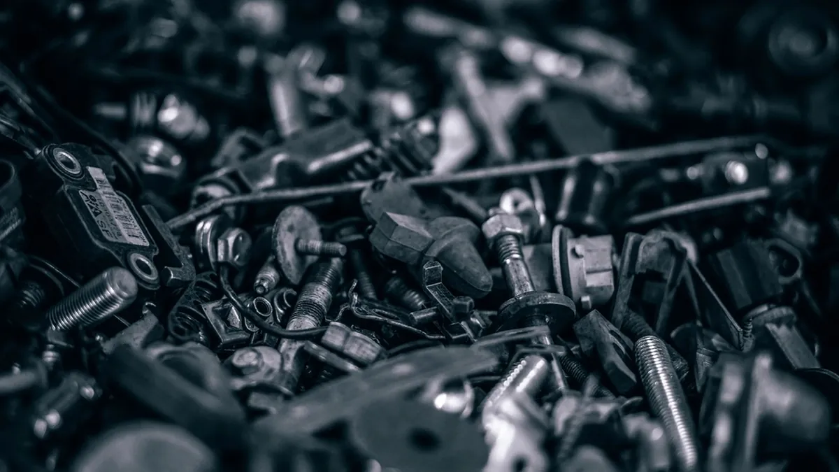 A pile of loose screws, nuts and metal parts, photographed close up in black and white.