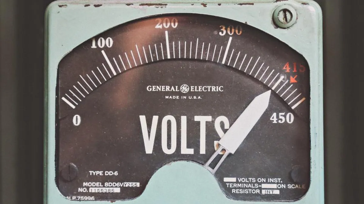 Il quadrante di un vecchio voltmetro analogico, con la lancetta vicino alla fine della scala.