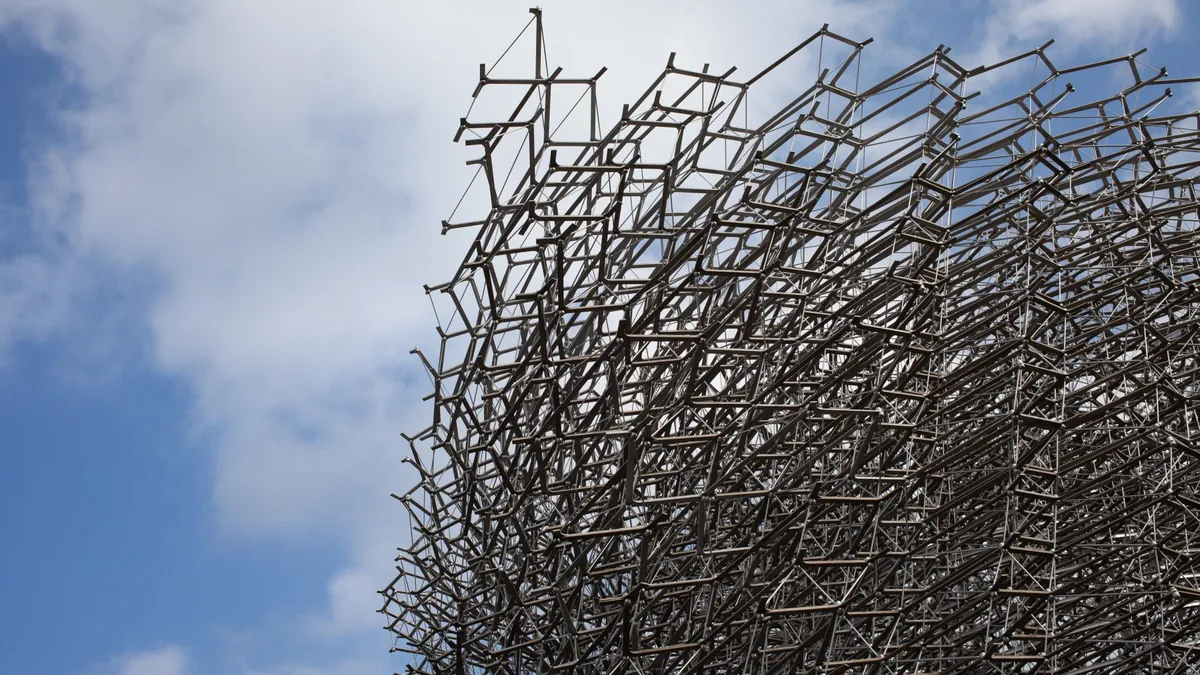 Estructura metálica de celosía abierta recortada contra el cielo, con la retícula vista desde abajo.